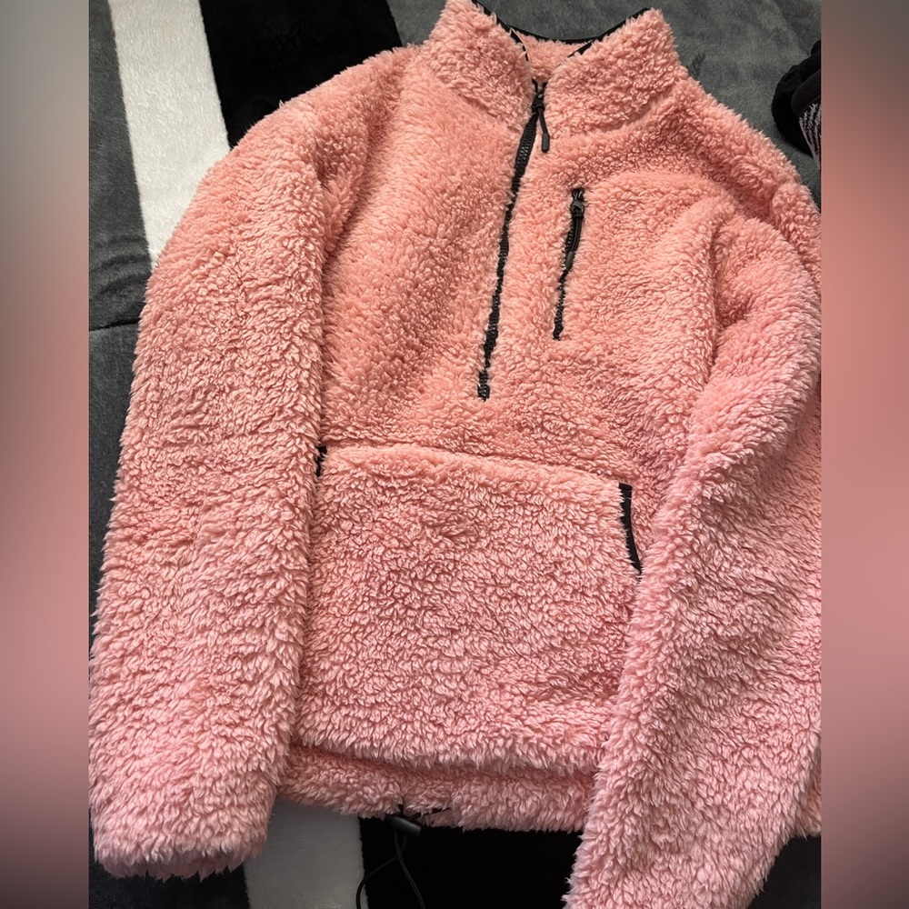 Pink fuzzy sweater. Has a pockets and on zip up pocket.